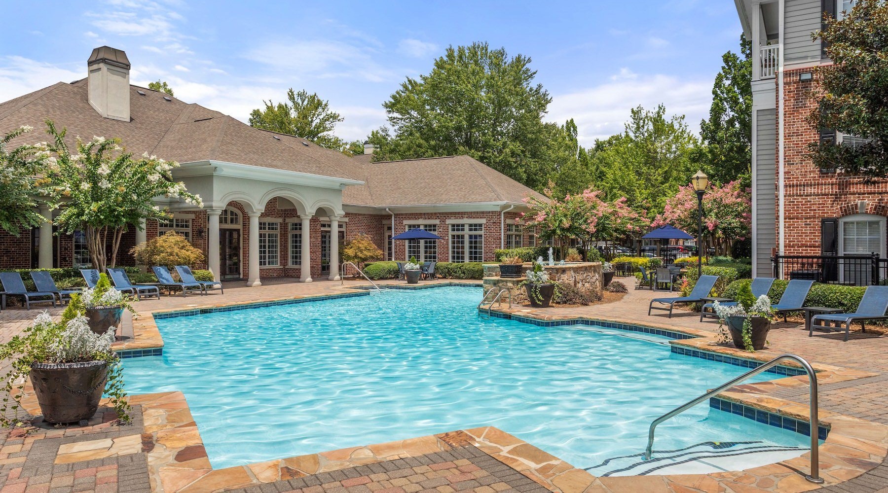 Shimmering resort-style pool pool with lounge chairs and plants